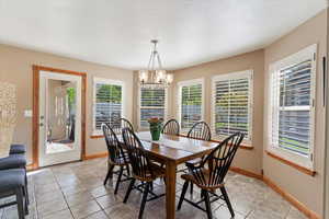 Dining space featuring healthy amount of natural light, a chandelier, light tile patterned flooring, and baseboards