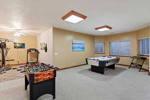 Rec room featuring carpet floors, baseboards, and ceiling fan