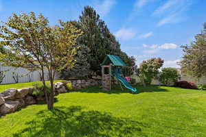 View of yard featuring rock terracing a playground