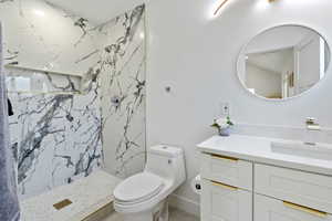 Bathroom with vanity, a marble finish shower, and toilet