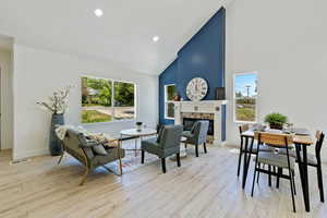 Living room with high vaulted ceiling, a tile fireplace, light wood-style flooring, baseboards, and recessed lighting