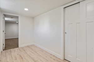 Unfurnished room featuring light wood-style flooring, baseboards, a textured ceiling, and recessed lighting