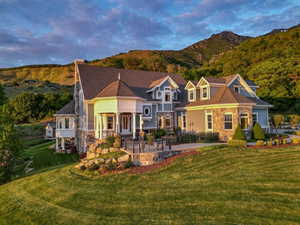 View of front of property with a patio area, a front lawn, a mountain view, and stone siding