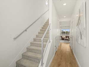 Staircase featuring recessed lighting, wood-type flooring, and baseboards