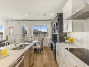 Kitchen with extractor fan, a sink, black electric stovetop, light wood finished floors, and recessed lighting