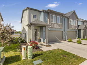 View of front of home featuring an attached garage, board and batten siding, concrete driveway, and a front lawn