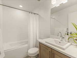 Bathroom with toilet, tiled shower / bath, and vanity