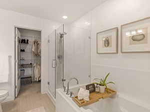 Bathroom featuring a shower stall, a garden tub, a spacious closet, and toilet