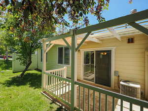 Wooden deck with central air condition unit, a yard, and a pergola