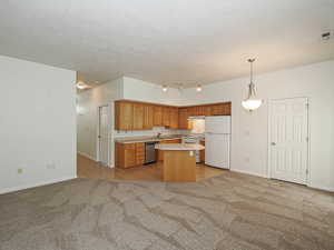 Kitchen with white appliances, light colored carpet, a sink, light countertops, and baseboards