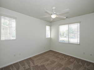 Carpeted empty room with ceiling fan and baseboards