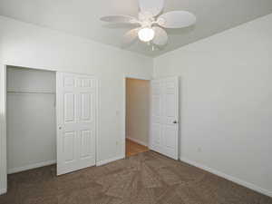 Unfurnished bedroom with carpet floors, a closet, baseboards, and a ceiling fan