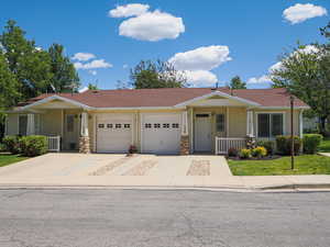 View of front facade featuring a porch, an attached garage, concrete driveway, and a front lawn