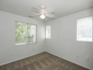 Carpeted empty room with baseboards and a ceiling fan