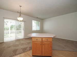 Kitchen featuring open floor plan, light colored carpet, hanging light fixtures, and light countertops