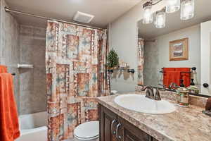 Bathroom with toilet, vanity, and shower / tub combo with curtain