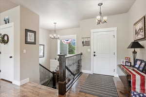 Foyer entrance with a chandelier, wood finished floors, and baseboards