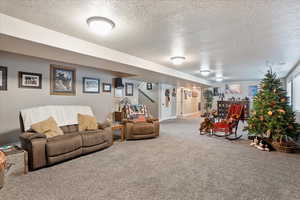 Living area with a textured ceiling, carpet floors, stairs, and baseboards