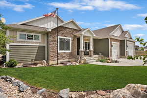 Craftsman house with board and batten siding, stone siding, driveway, and a front yard