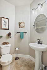 Half bath with toilet, baseboards, and a sink