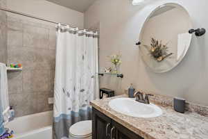 Bathroom featuring toilet, shower / bath combination with curtain, and vanity
