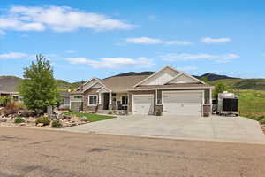 Craftsman house featuring a garage, concrete driveway, a mountain view, a shingled roof, and stone siding