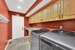 Laundry area featuring cabinet space, independent washer and dryer, and sink