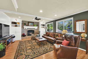 Living area featuring ornamental molding, a fireplace, a ceiling fan, hardwood floors, and a textured ceiling