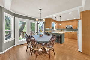 Dining room with a textured ceiling, hardwood floors, crown molding, a chandelier, and recessed lighting