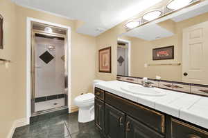 Downstairs Bathroom featuring a steam shower stall, toilet, baseboards, and a textured ceiling