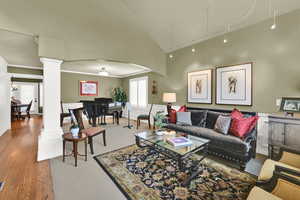 Living room featuring ornate columns, attic access, crown molding, lofted ceiling, and arched walkways