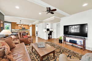 Open-concept kitchen/living room featuring a chandelier, crown molding, hardwood floors, a ceiling fan, and recessed lighting