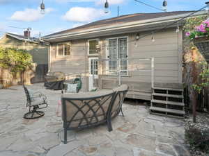 Rear view of house featuring a fenced backyard, an outdoor living space, and a patio area