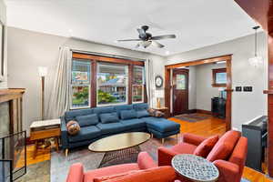Living area with wood finished floors, a premium fireplace, a ceiling fan, and baseboards