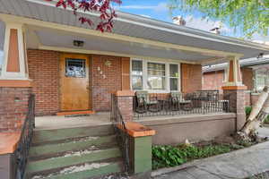 View of exterior entry featuring brick siding and covered porch