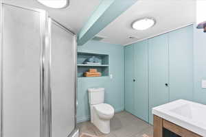 Bathroom with a stall shower, toilet, and built in shelves