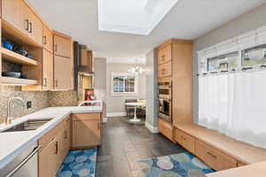 Kitchen with a sink, appliances with stainless steel finishes, decorative backsplash, wall chimney exhaust hood, and light countertops