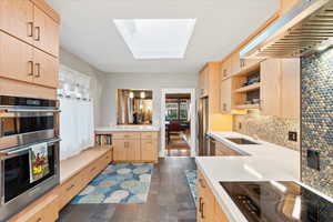 Kitchen with light brown cabinets, a sink, appliances with stainless steel finishes, and extractor fan