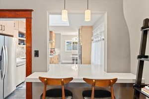 Kitchen with stainless steel fridge with ice dispenser, dishwasher, a breakfast bar, a sink, and a chandelier