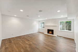 Unfurnished living room featuring healthy amount of natural light, baseboards, wood finished floors, and recessed lighting