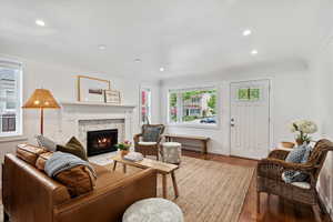 Living area with natural light, a premium fireplace, wood floors, and recessed lighting