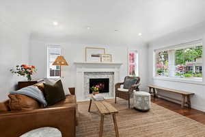 Living area with wood finished floors, a high end fireplace, crown molding, recessed lighting