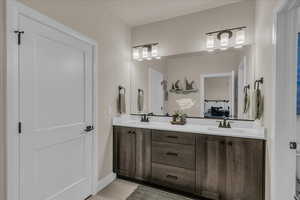 Bathroom with connected bathroom, double vanity, tile patterned floors, and baseboards