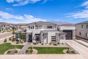 Contemporary home with stucco siding, stone siding, concrete driveway, and a mountain view