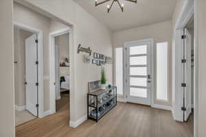Foyer entrance with wood finished floors, a chandelier, and baseboards