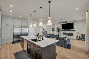 Kitchen with a sink, stainless steel appliances, light wood finished floors, ceiling fan, and pendant lighting