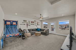 Carpeted living room with a ceiling fan, a textured ceiling, recessed lighting, and baseboards