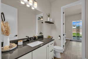 Bathroom with vanity, toilet, wood finished floors, and baseboards