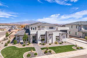 Modern home featuring stucco siding, stone siding, concrete driveway, a tile roof, and a mountain view
