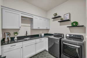 Washroom with washing machine and clothes dryer, cabinet space, and dark tile patterned flooring